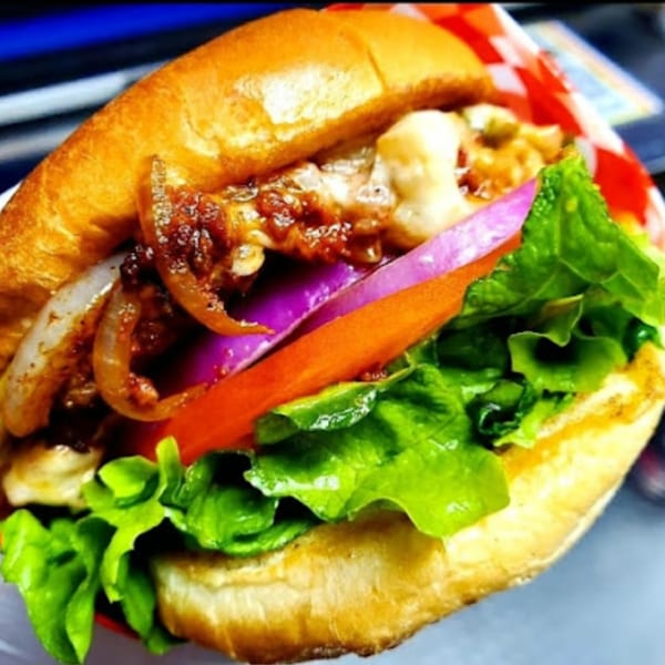 Close-up of a tex-mex burger with melted cheese, caramelized onions, red onion, tomato, and lettuce.