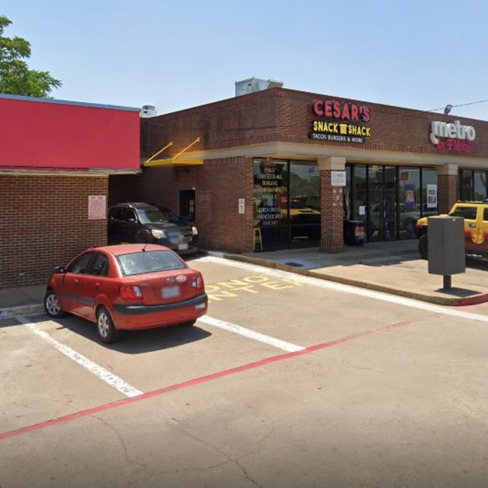 Exterior of Cesar's Snack Shack, a brick building with a drive-thru, and cars parked outside.