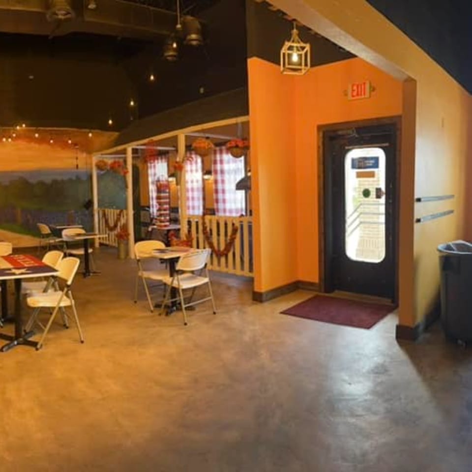 Interior of Cesar's Snack Shack with tables, chairs, and a vibrant orange wall with an exit sign.