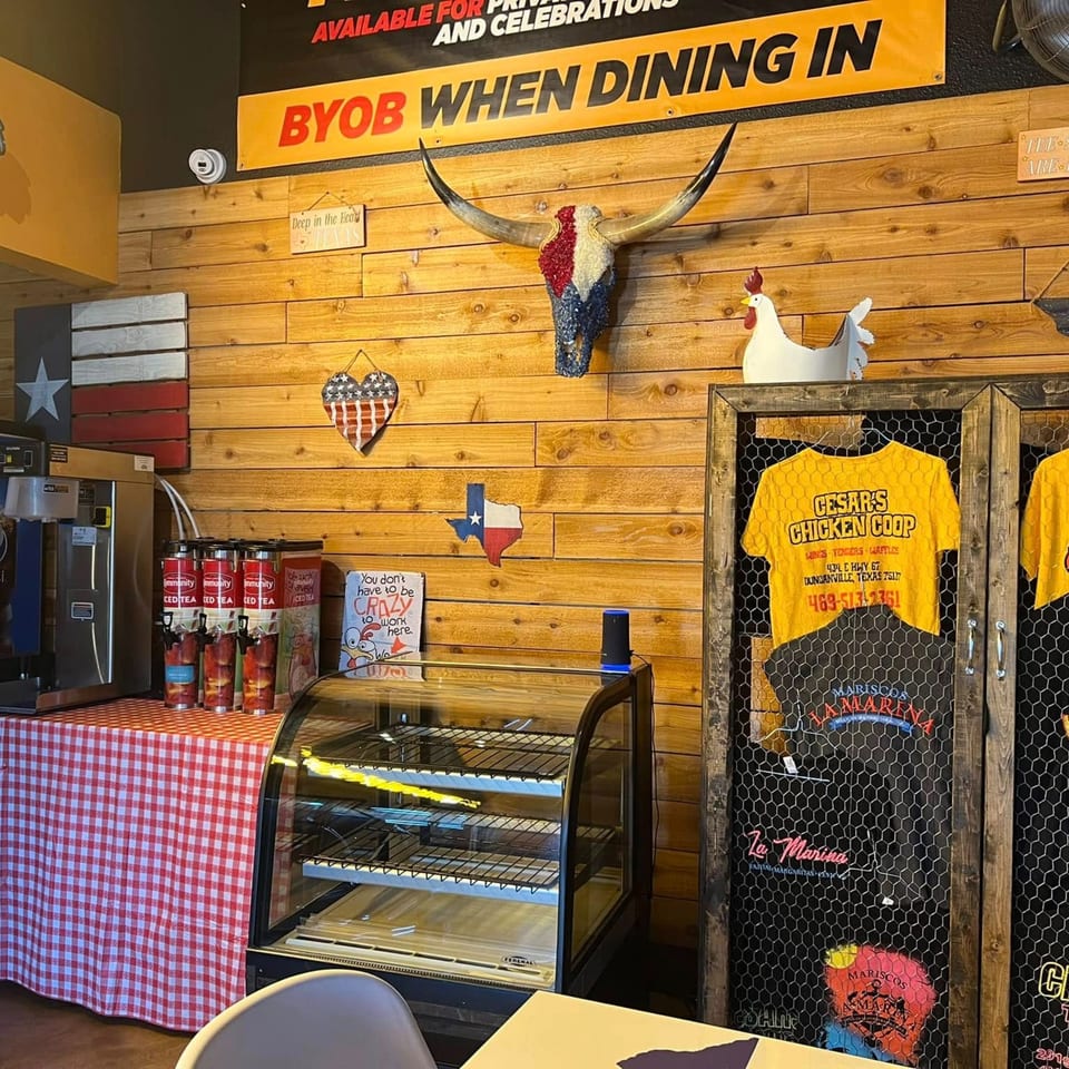 Interior of Cesar's Snack Shack with a Texas flag, bull skull, and branded merchandise on a wooden wall.